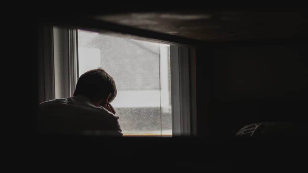 man staring out the window depressed